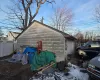 View of snow covered exterior with a garage and an outdoor structure