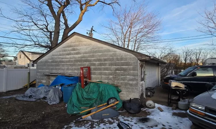 View of snow covered exterior with a garage and an outdoor structure