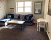 Living room featuring dark colored carpet and a wall mounted AC