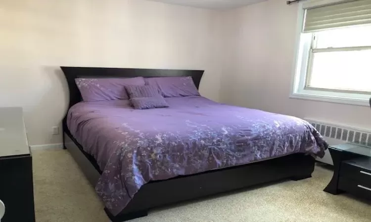 Carpeted bedroom with radiator heating unit