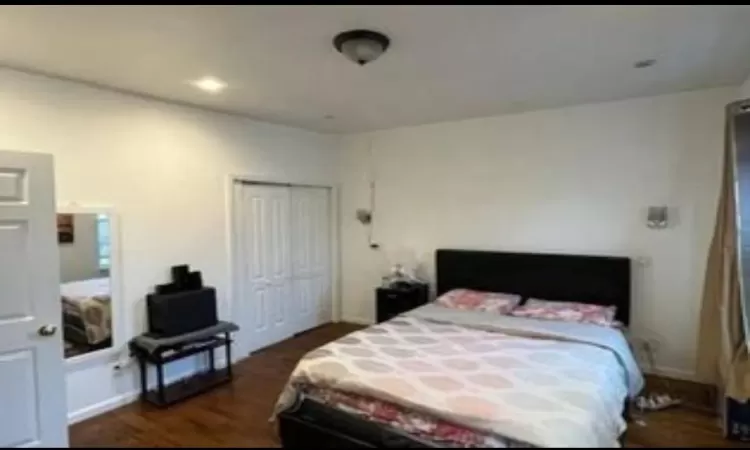 Bedroom with dark hardwood / wood-style flooring and a closet