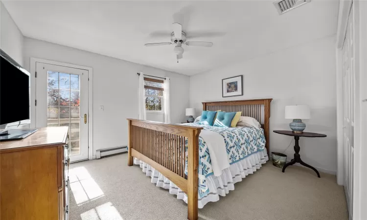 Bedroom featuring light carpet, access to outside, a baseboard radiator, and ceiling fan