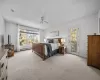 Bedroom featuring access to exterior, light colored carpet, baseboard heating, and ceiling fan