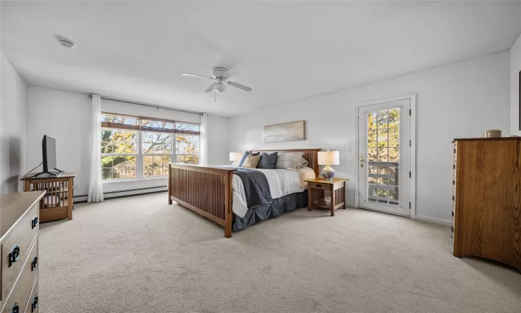 Bedroom featuring access to exterior, light colored carpet, baseboard heating, and ceiling fan