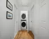 Clothes washing area with stacked washing maching and dryer and light hardwood / wood-style floors