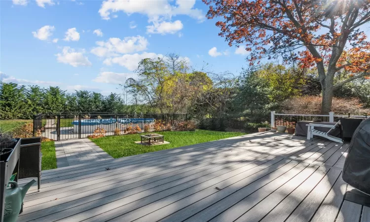 Deck with a swimming pool, an outdoor fire pit, and a lawn