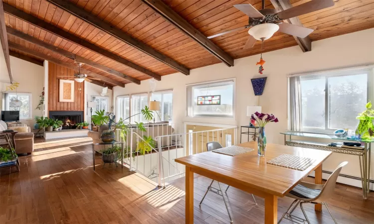 Dining space with wood ceiling, lofted ceiling with beams, dark hardwood / wood-style flooring, a fireplace, and a baseboard heating unit