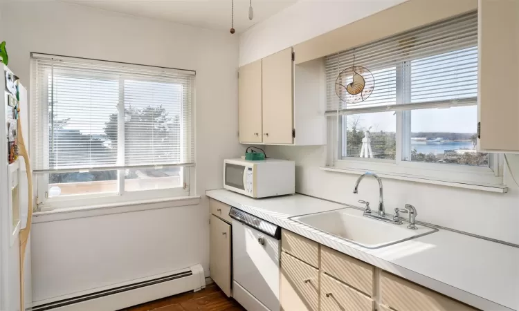 Kitchen with white appliances, decorative light fixtures, sink, and a baseboard heating unit