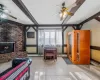 Tiled living room featuring beamed ceiling, ceiling fan, a fireplace, and a wall unit AC