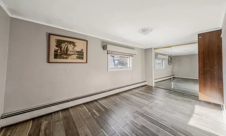 Unfurnished room with ornamental molding, a baseboard heating unit, and hardwood / wood-style floors