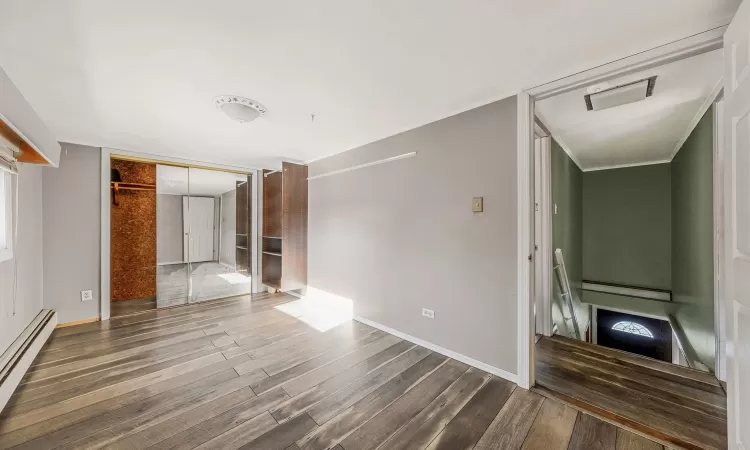 Unfurnished living room featuring dark wood-type flooring and a baseboard radiator