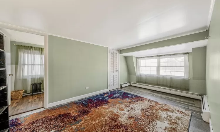 Spare room featuring ornamental molding, hardwood / wood-style floors, and a baseboard heating unit