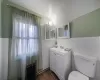 Bathroom featuring radiator, wood-type flooring, lofted ceiling, vanity, and toilet