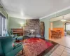 Living room featuring tile patterned flooring, a brick fireplace, wooden walls, and ornamental molding