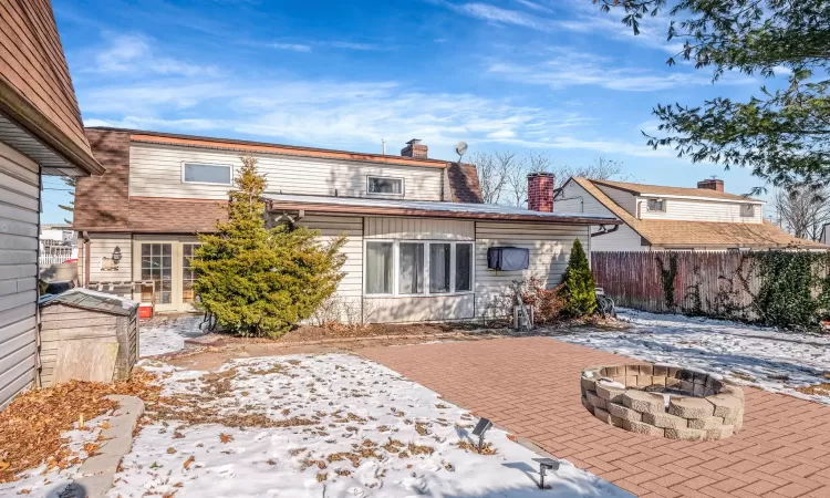 Snow covered back of property with a patio and an outdoor fire pit