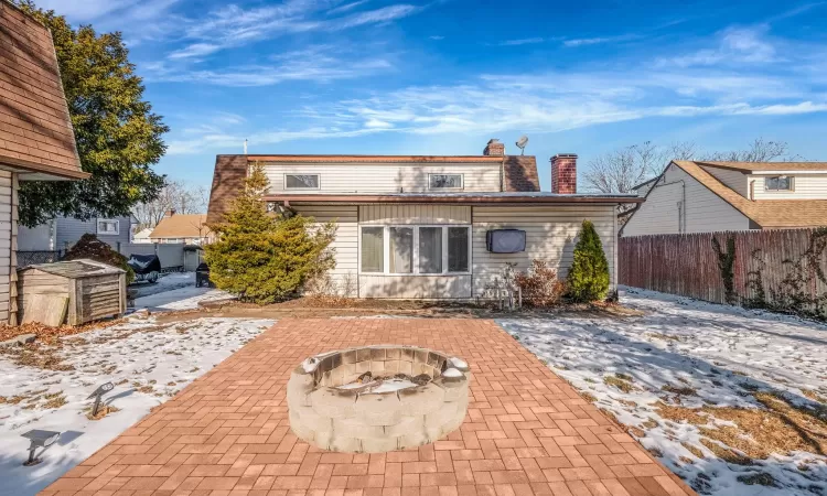 Snow covered house featuring an outdoor fire pit and a patio area