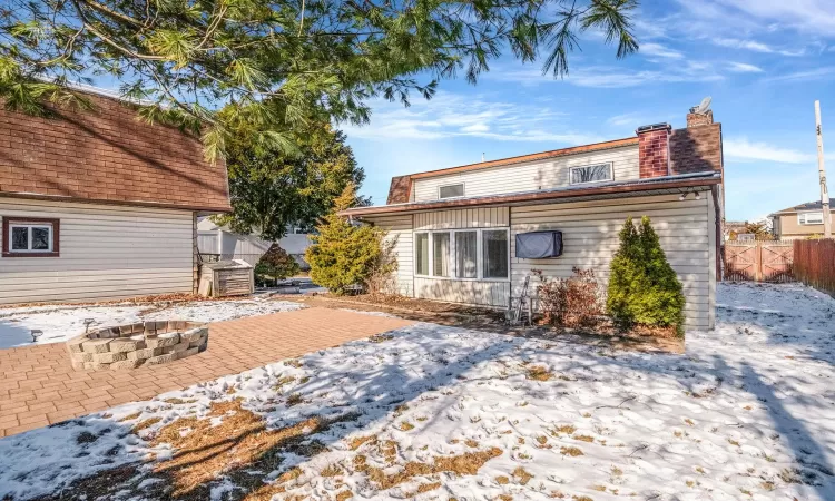 Snow covered back of property with a patio and an outdoor fire pit