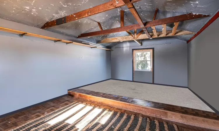 Unfurnished room with vaulted ceiling and parquet floors