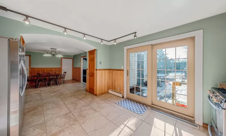 Entryway with a baseboard heating unit, light tile patterned floors, and wooden walls