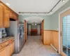 Kitchen featuring wood walls, a baseboard radiator, light tile patterned floors, light stone counters, and stainless steel fridge with ice dispenser