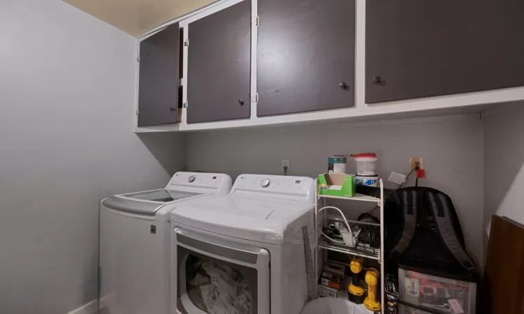 Laundry room featuring washer and clothes dryer and cabinets