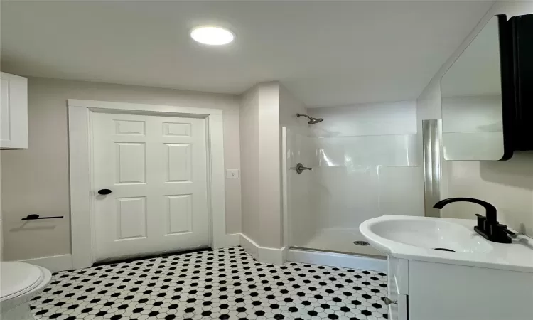 Bathroom featuring vanity, tile patterned floors, toilet, and a shower