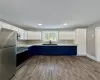 Kitchen featuring blue cabinets, white cabinetry, sink, stainless steel appliances, and dark wood-type flooring