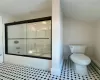 Bathroom featuring baseboard heating, shower / bath combination with glass door, and toilet