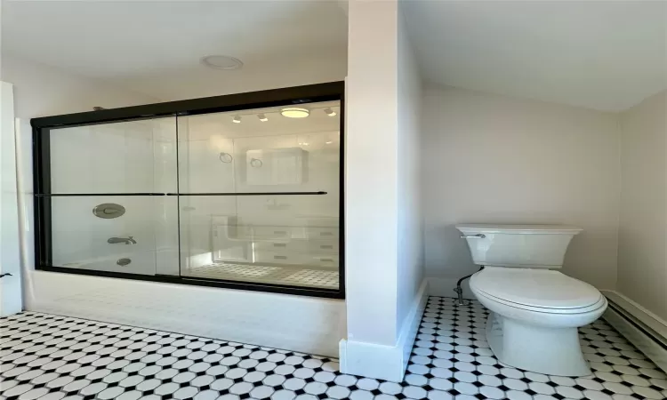 Bathroom featuring baseboard heating, shower / bath combination with glass door, and toilet