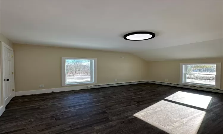 Bonus room featuring plenty of natural light, lofted ceiling, dark hardwood / wood-style flooring, and baseboard heating