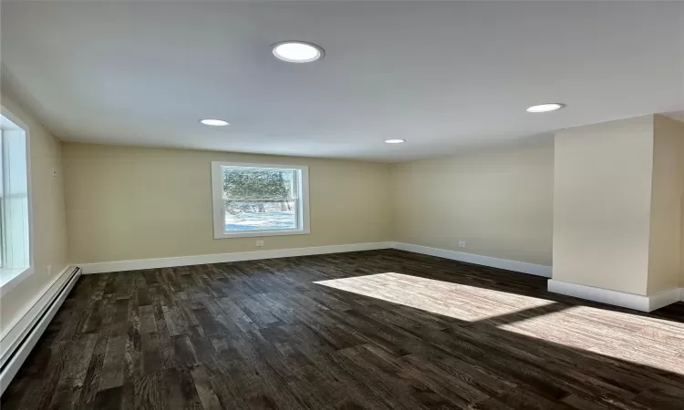 Unfurnished room featuring a baseboard radiator and dark hardwood / wood-style flooring