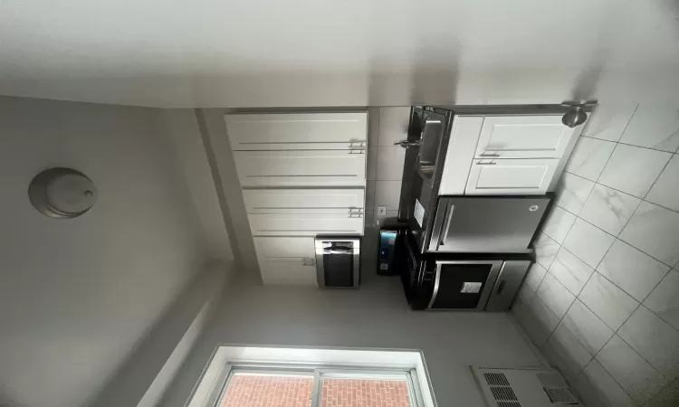 Kitchen featuring radiator, sink, dishwasher, range, and white cabinets