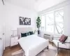 Bedroom featuring a wall mounted AC, multiple windows, and light wood-type flooring