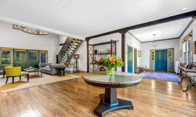 Foyer entrance featuring an inviting chandelier, radiator heating unit, light hardwood / wood-style floors, and beam ceiling