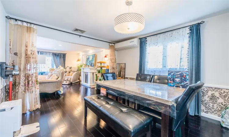 Dining space featuring dark wood-type flooring and a wall mounted air conditioner