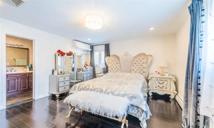 Bedroom with ensuite bath, a wall mounted AC, and sink