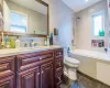 Full bathroom featuring tiled shower / bath, tile walls, vanity, and toilet