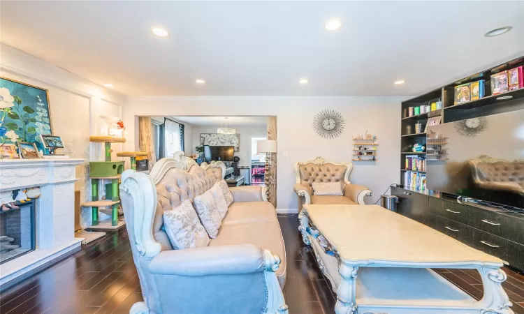 Living room featuring dark hardwood / wood-style flooring, crown molding, and a fireplace