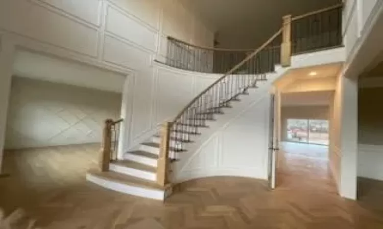 Staircase featuring a towering ceiling and parquet floors