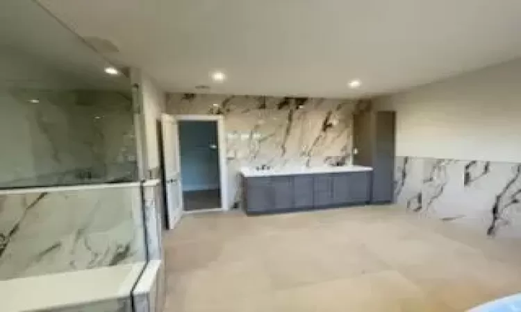 Bathroom featuring tile walls, vanity, and walk in shower