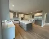 Kitchen featuring wall chimney exhaust hood, sink, white cabinetry, a kitchen island, and light hardwood / wood-style floors