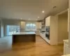 Kitchen featuring plenty of natural light, wall chimney range hood, a kitchen island, and white cabinets