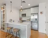 Kitchen featuring sink, light hardwood / wood-style flooring, a breakfast bar, stainless steel appliances, and decorative light fixtures