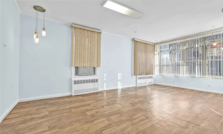 Unfurnished living room with hardwood / wood-style floors, radiator heating unit, and ornamental molding