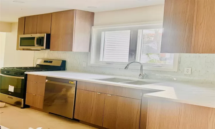 Kitchen with sink, decorative backsplash, and appliances with stainless steel finishes