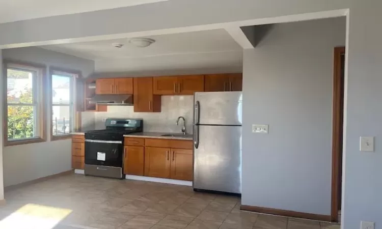 Kitchen with stainless steel appliances, tasteful backsplash, sink, and exhaust hood