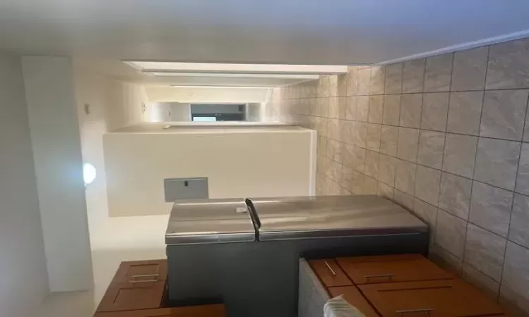 Kitchen featuring fridge, electric panel, and light tile patterned floors