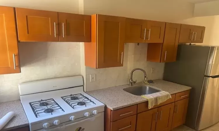 Kitchen with stainless steel fridge, sink, gas range gas stove, and backsplash