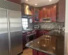 Kitchen featuring sink, extractor fan, appliances with stainless steel finishes, dark stone counters, and backsplash