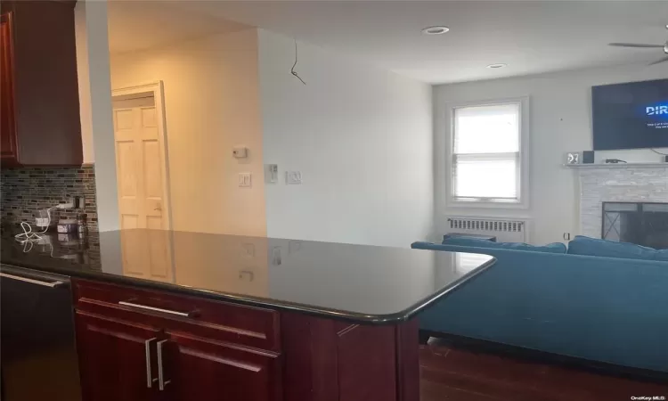 Kitchen featuring radiator, dark hardwood / wood-style flooring, decorative backsplash, ceiling fan, and kitchen peninsula